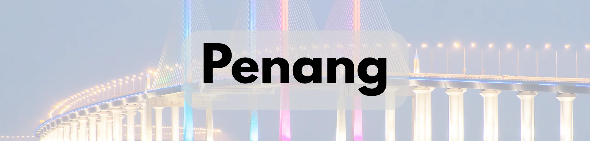 A brightly illuminated Penang Bridge at night, featuring colourful cable lights and rows of glowing streetlights, with the word “Penang” prominently displayed.